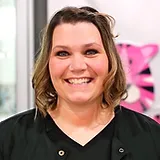 Woman smiling at camera in dental office with pink background decor