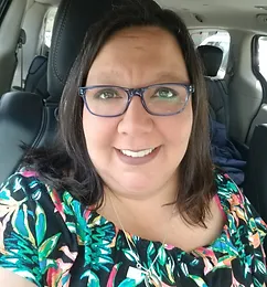 Woman wearing glasses and colorful floral shirt smiling in car interior
