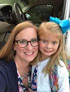 Adult and child smiling together at dental office, child wearing blue bow.