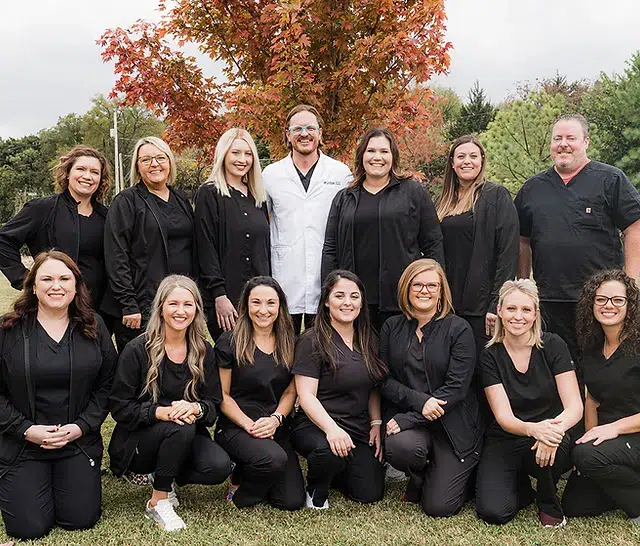 Safari Smiles Children's Dentistry team posing together outdoors in professional black attire.