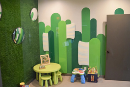 Colorful green cactus-themed dental office display with yellow stool and toy figures in child-friendly setting.