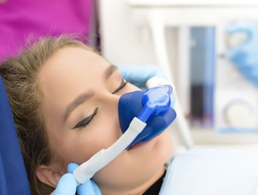 Young girl using blue and white inhaler or dental device in clinical dental office setting.